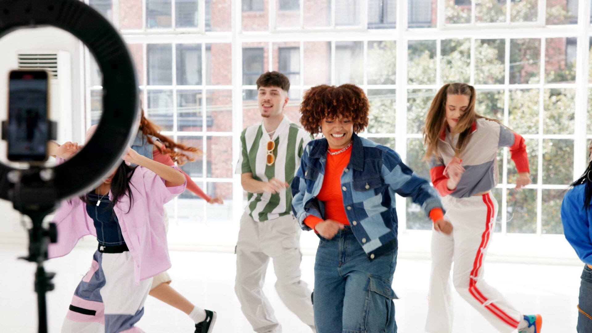 A group of influencers dancing in front of a ring light and content set. They're all smiling and engaging with the video.