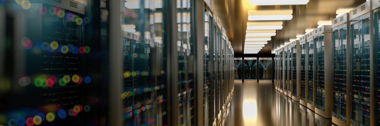 A server room in a data center with rows of multiple computer racks powered on, showing different colored lights.