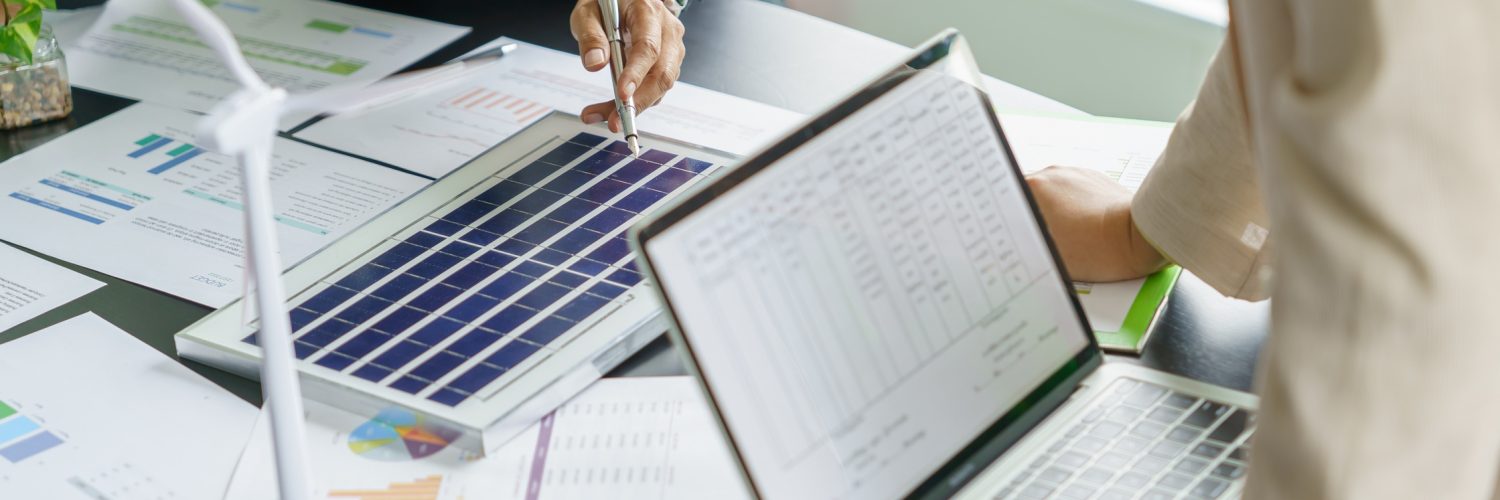 Two people standing around a table and examining documents and models with information about renewable energy options they could use.