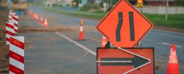Along a section of the road are the signals for construction. It has a sign that the lanes are narrowing and cones.