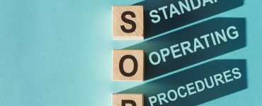 Three wooden blocks with the letters "SOP" on them cast shadows that spell out "Standard Operating Procedures."