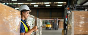 A group of individuals wearing suits reviews charts and solar panels on a table while one person holds a small globe.
